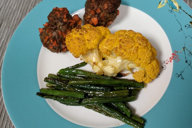 Plate of three meatballs with carrot in them, cauliflower and green beans
